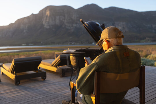 elderly man sitting on outdoor deck of resort overlooking Klein Mountains and Lagoon, Stanford, South Africa