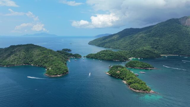 Drone video captures lush green islands and vivid blue waters of Ilha Grande, Angra dos Reis, under dramatic clouds.