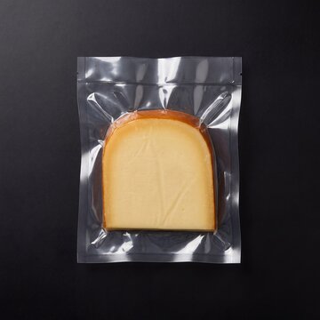 A slice of delicious hard cheese, vacuum-sealed in clear plastic packaging, ready for consumption, offering a savory culinary experience.