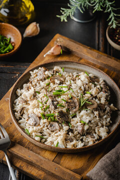 Risotto with mushrooms and herbs on an old wooden background. Rustic style.
