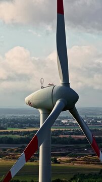 Large wind turbine rotating in open countryside with distant town and fields
