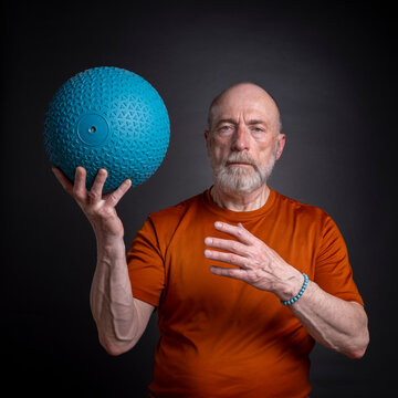 senior man (in late 60s) is exercising with a heavy slam or medicine  ball, activity and fitness over 60 concept