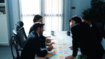 Obraz premium Top view of business team discuss about marketing strategy while smart manager enter meeting and talking about plan. Diverse people brainstorming idea by using sticky notes at board room. Directorate.