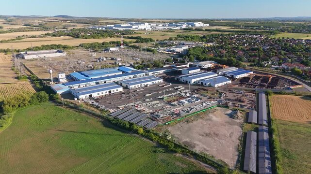 G&ouml;d, Hungary electric substation and battery factory within an industrial park, with power lines, roads and fields in a suburban landscape, aerial view.