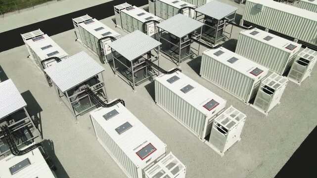 Aerial view of a modern battery energy storage system with large industrial containers and cooling units, a key component for stabilizing the power grid and supporting renewable energy sources