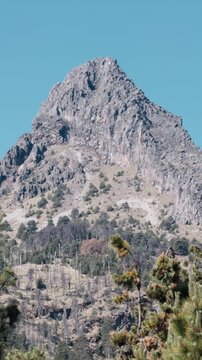 The Rocky Peak Of Nevado de Colima Rises Above A Dense Pine Forest In Jalisco, Mexico. Vertical, Aerial Shot