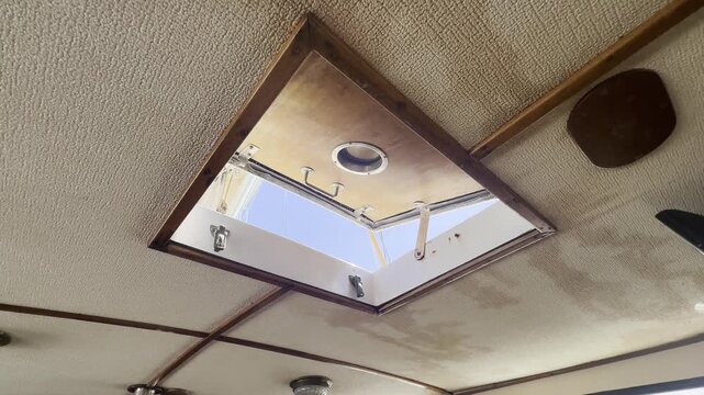 Open ceiling hatch inside a sailboat cabin providing natural light and ventilation, showing nautical interior, marine design and onboard living.