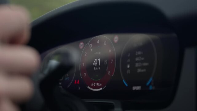 Close-up of a Porsche GTS digital instrument cluster as the speed increases while driving through the Alps.