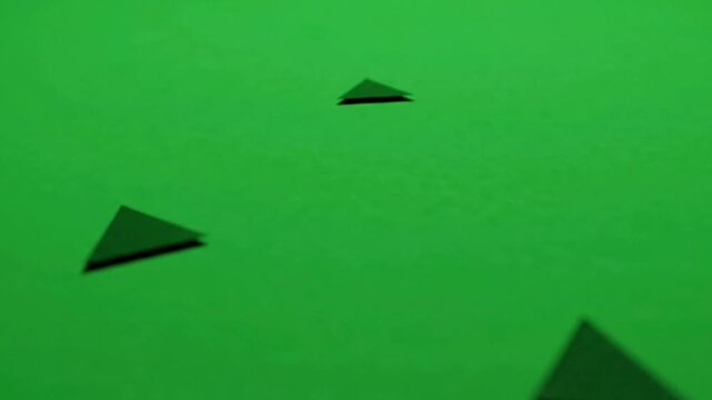 Minimalist black triangles floating on vibrant green background, abstract motion