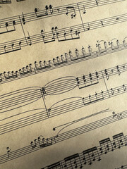 Fototapeta premium Close up of sheet music with musical notes and textured paper. Musical notes on sheet music, clear details of composition. Black notes, musical score, sheet music, musical notation, classical music