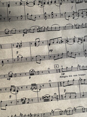 Fototapeta premium Close up of sheet music with musical notes and textured paper. Musical notes on sheet music, clear details of composition. Black notes, musical score, sheet music, musical notation, classical music