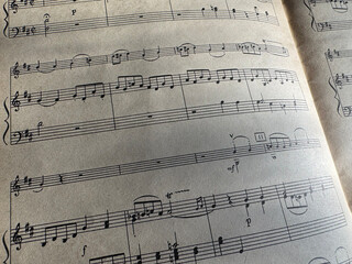 Fototapeta premium Close up of sheet music with musical notes and textured paper. Musical notes on sheet music, clear details of composition. Black notes, musical score, sheet music, musical notation, classical music