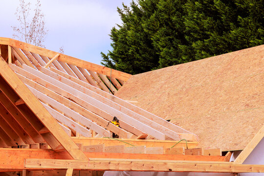 Construction workers build roof structure for new home in suburban area