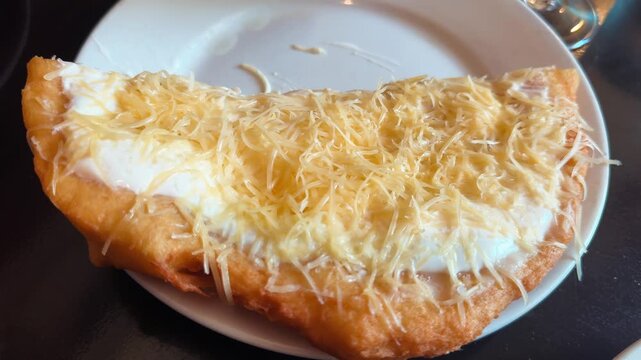 Traditional Hungarian langos folded with melted cheese and generously topped with grated cheese. Popular Hungarian street food served fresh in a restaurant. High quality 4k footage