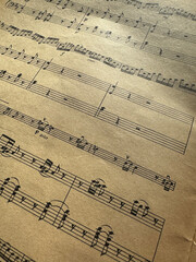 Fototapeta premium Close up of old sheet music with musical notes. Old musical score - no lyrics. Atmospheric music background with notes on old brown paper. For scrapbooking collage, journal design, and craft projects.