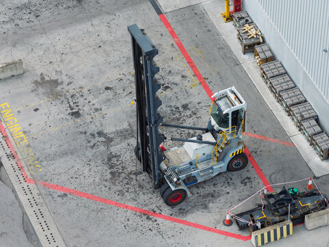 Reach Stacker Maneuvering in a Shipping Terminal During the Daytime With Pallets Parked Nearby