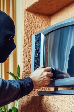 A person wearing a hoodie looks at a TV, possibly watching a show or movie. vertical frame