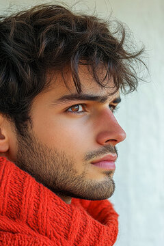 A man leans against a wall wearing a red scarf, possibly waiting or observing something. vertical frame