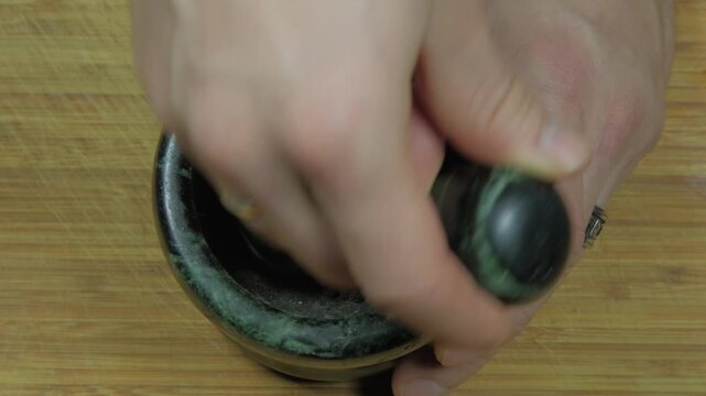 Mixing spices in a mortar and pestle for cooking in a kitchen setting, close-up