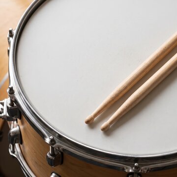 Drumhead with wooden drumsticks resting across snare drum