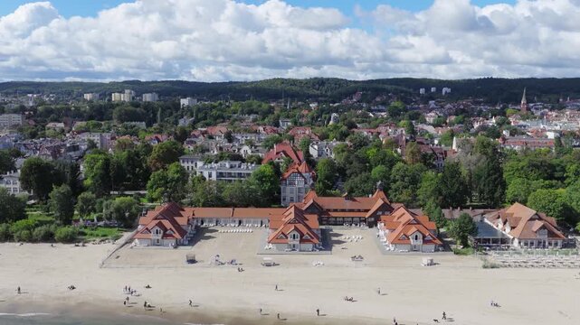 Aerial view of beach buildings and sandy coastline with people walking along the shore in Gdansk, Pomeranian Voivodeship, Poland.