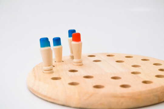 Wooden Round Peg Board Game With Blue And Red Tops On White Background
