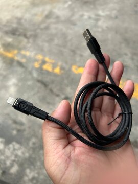 The image shows a black, nylon-braided USB-A to Lightning cable featuring a rugged, angular mecha-style connector housing on the Lightning end.