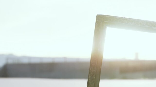 A weathered frame stands against a serene shoreline, capturing the soft sunlight of dawn. The calm water reflects the warm glow, creating a peaceful atmosphere filled with natures beauty.