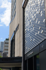 Fototapeta premium perspective view of exterior building facades and signs of Van Cleef & Arpels, a jewelry store, and Burberry, a clothing store, located at 100 Bloor St W, Toronto