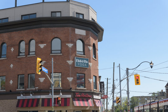 historic building facade and signs of Tim Hortons and Ebb & Flo Studio, located at 95 Danforth Av at Broadview Av, Toronto