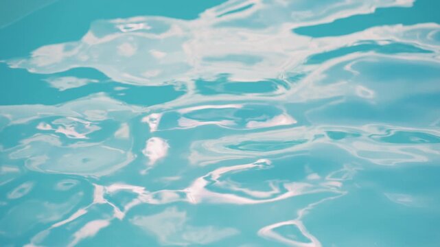 Calm blue water ripples gently across frame reflecting light and creating soft white patterns. continuous movement of small waves suggests serene aquatic environment with no other objects