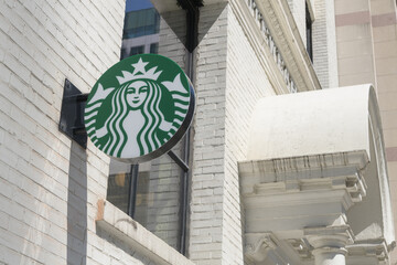 Obraz premium wall-mounted round projecting logo sign outside Starbucks coffee shop at the historic Eclipse Whitewear Building, 322 King St W, Toronto