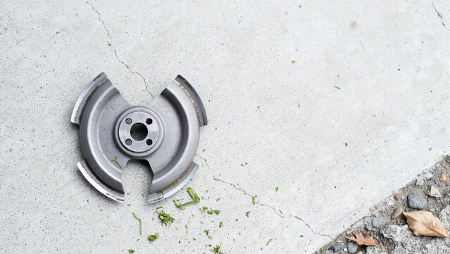Broken metal disc with four notches on cracked concrete keywords: metal, disc, broken, damaged