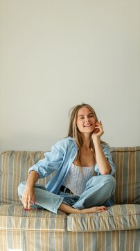 Young woman with braided hair relaxing on a striped couch in casual attire