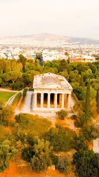 Vertical video. Athens, Greece. Temple of Hephaestus. Athenian Agora in the light of the morning sun. Summer. Drone footage, Departure of the camera. Rich colors