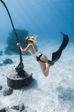 Free diver woman holding a rope while exploring a coral reef underwater