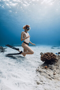 Female free diver with fins underwater posing on sandy bottom