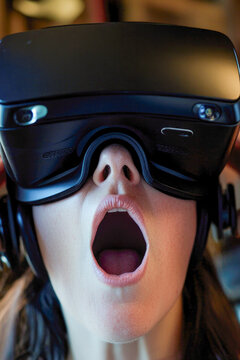 A person wearing a virtual reality headset with their mouth open, showing curiosity and engagement. vertical frame