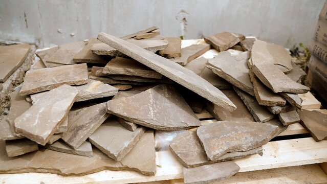 Irregularly shaped natural flagstone paving slabs piled on a wooden pallet for garden or patio construction