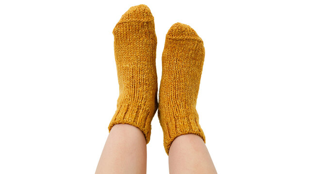 Isolated human legs and feet wearing cozy warm mustard yellow knitted socks, comfort and warmth.