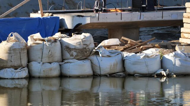 Sandbags creating flood protection barrier at construction site with water reflection