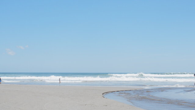 Scenic tropical beach with gentle ocean waves, sandy shoreline, and clear blue sky