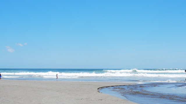 Scenic tropical beach with gentle ocean waves, sandy shoreline, and clear blue sky