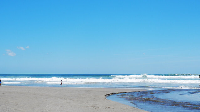 Scenic tropical beach with gentle ocean waves, sandy shoreline, and clear blue sky