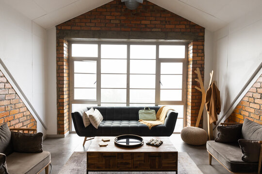 Dark tufted sofa is sitting centered in loft living room, showing coffee table and black tray