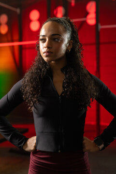 African American woman 20s standing in gym wearing black zip-top, maroon bottoms