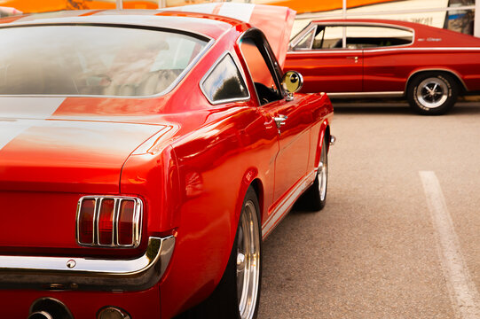 Classic retro red muscle car fastback parked at a car show exhibition during a sunny day, showcasing iconic vintage design, shiny chrome details, and powerful automotive heritage.