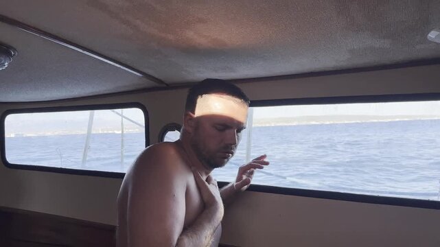 Man suffering from seasickness and nausea inside a sailboat cabin while traveling at sea, showing motion sickness, discomfort, dizziness and feeling unwell.