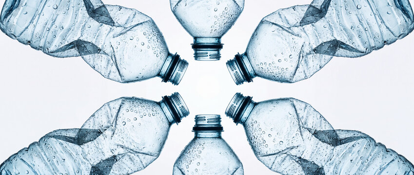 Plastic bottles crushed in a circular pattern with water droplets on a white background, representing eco waste recycling, environmental pollution control, and conservation