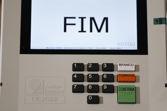 Close-up of a Brazilian voter pressing a button on an electronic voting machine at a polling station during the 2026 Brazilian elections, illustrating electronic voting, democracy, civic participation